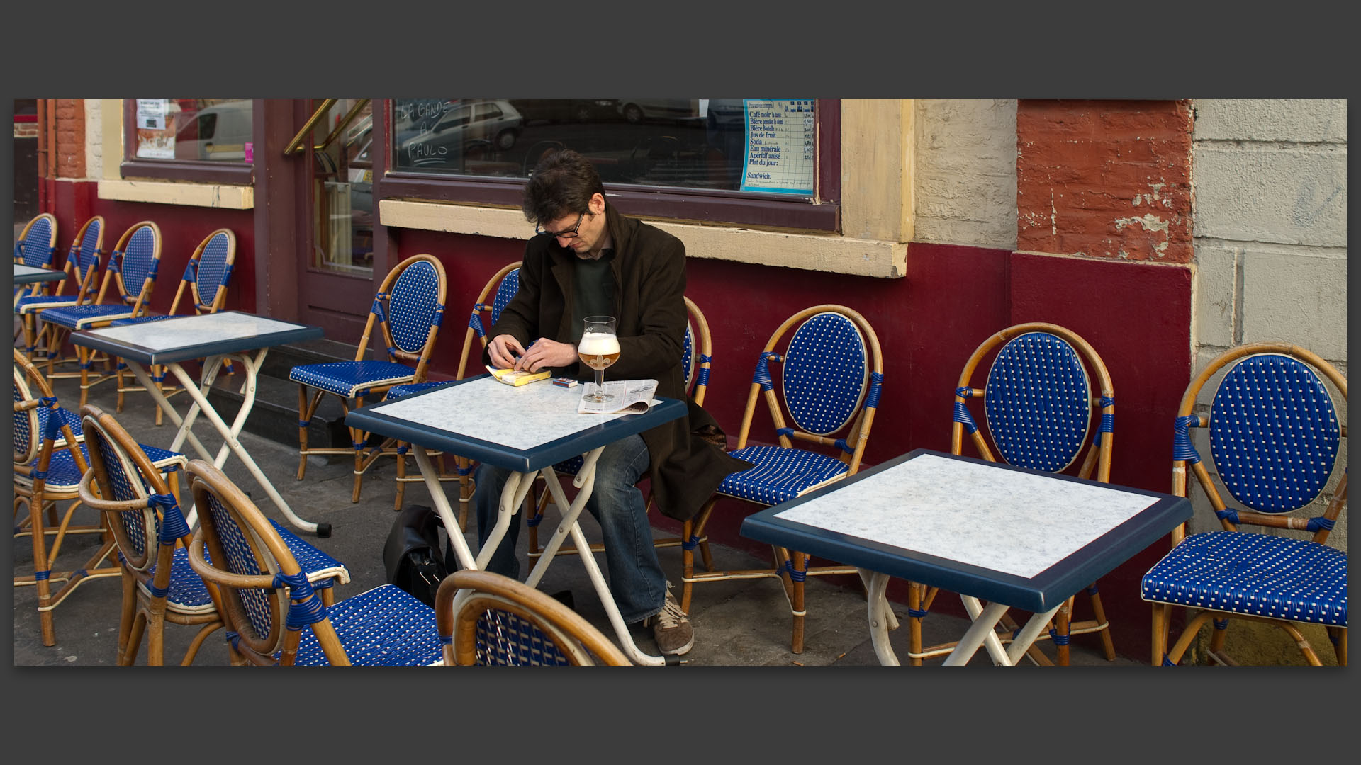 Jeune homme roulant une cigarette, à la terrasse du Presto, rue des Sarrazins, à Wazemmes, Lille.