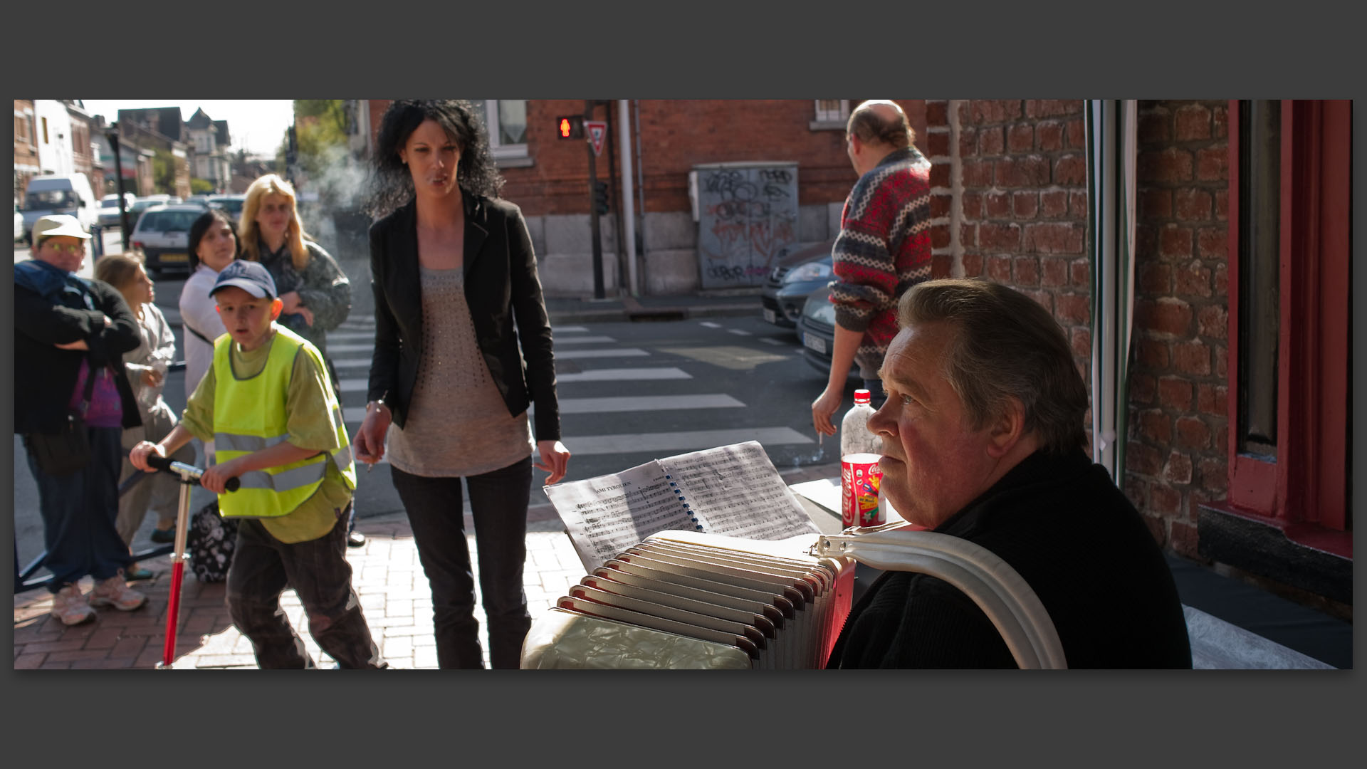 Accordéoniste et son public, pendant l'épreuve de marche athlétique, rue Jean-Jaurès, à Croix.