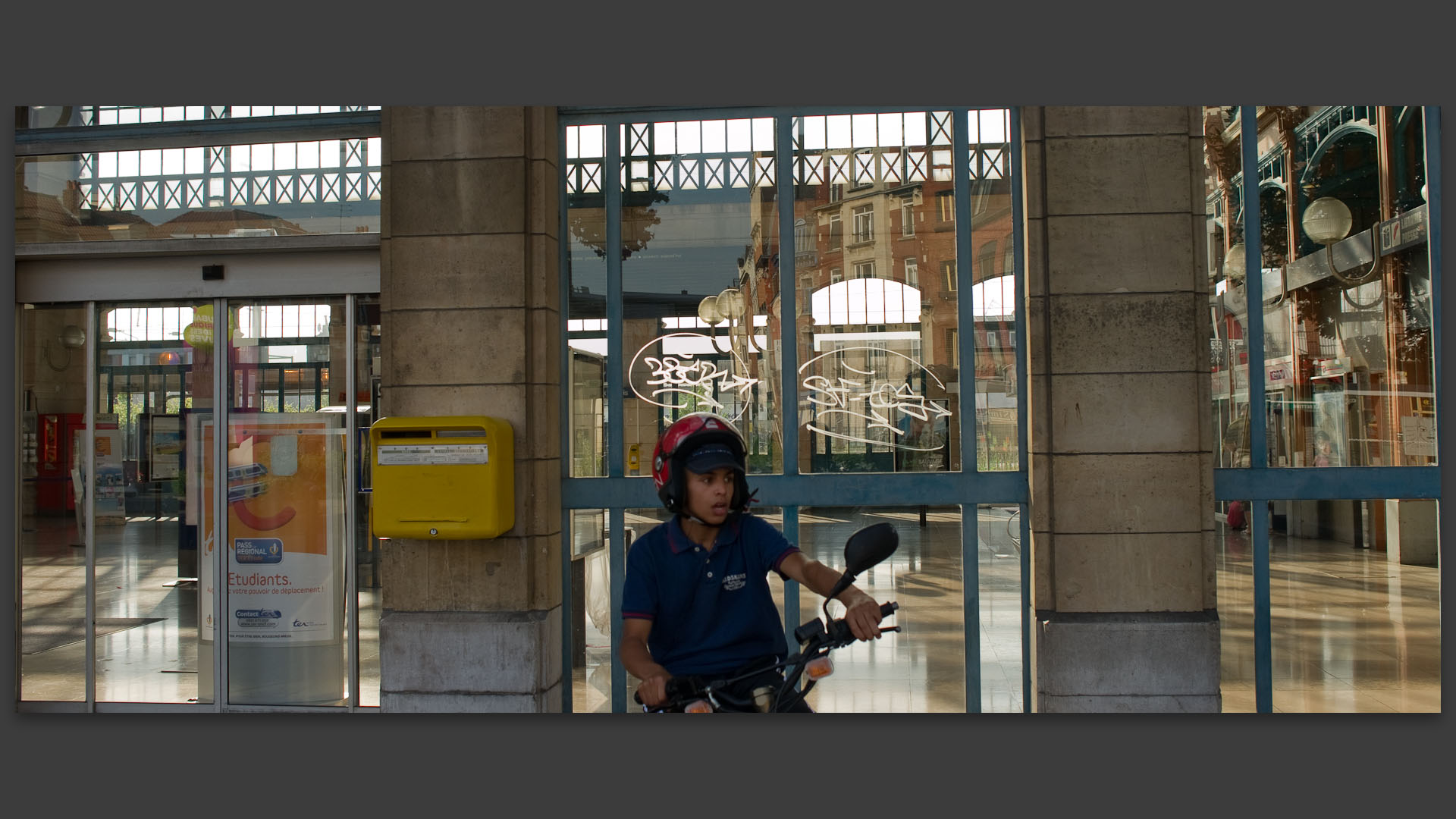 Jeune en scooter devant la gare de Roubaix.