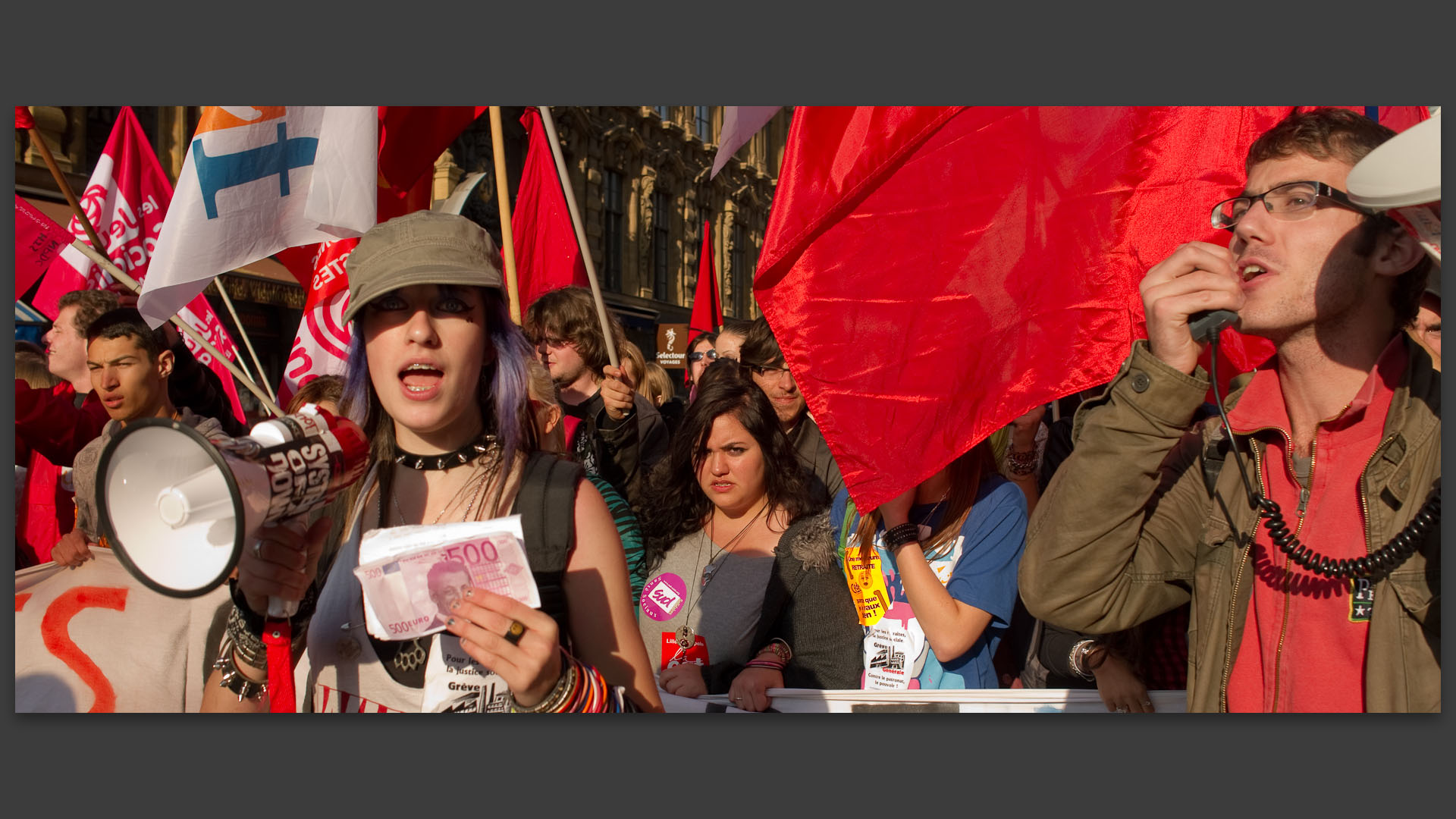 Jeune fille et jeune garçon criant des slogans dans des mégaphones pendant la manifestation contre la réforme des retraites.