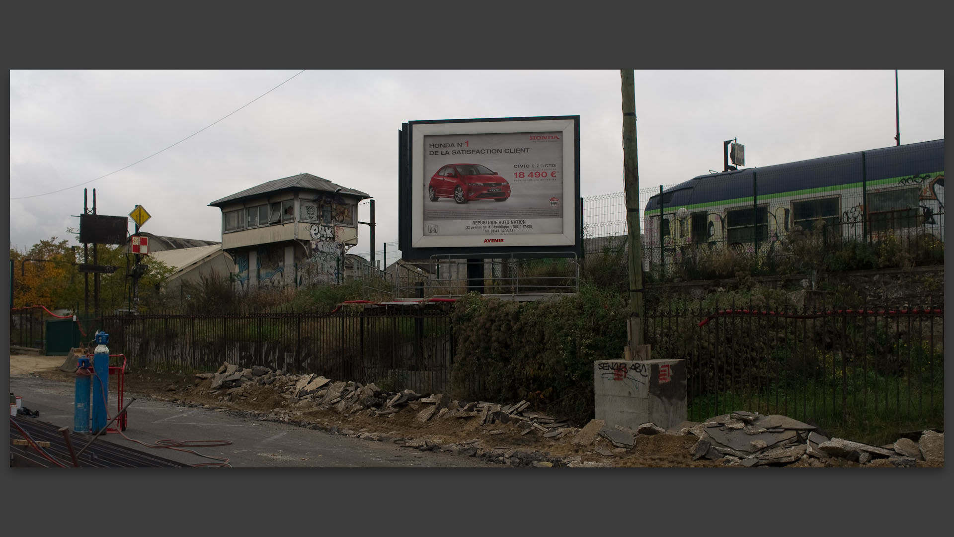 Affiche publicitaire pour une voiture à côté d'un vieux wagon de chemin de fer, boulevard Poniatowski, à Paris.