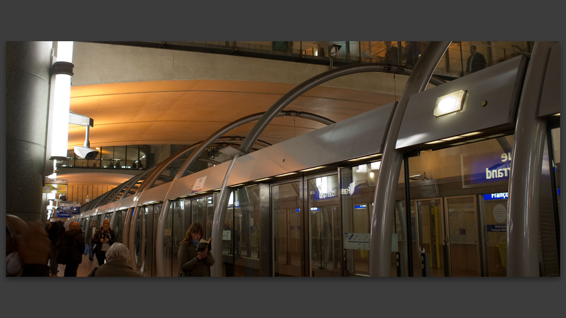 Femme lisant en attendant le métro, station François-Mitterrand, à Paris.