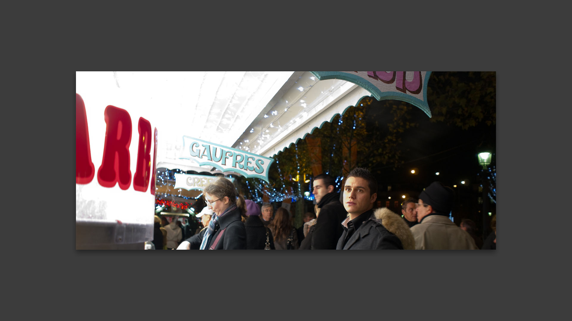 Homme devant une boutique de confiserie du marché de Noël, avenue des Champs Elysées, à Paris.