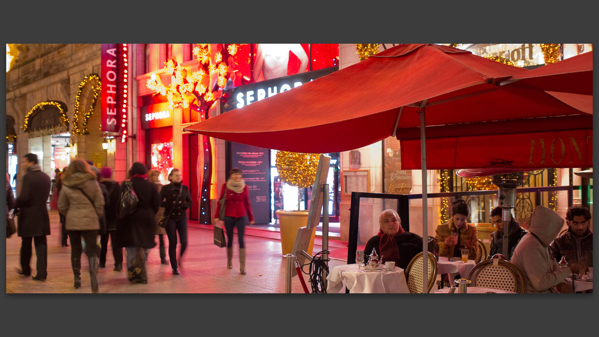 Homme attablé en terrasse devant la boutique Sephora, avenue des Champs Elysées, à Paris.