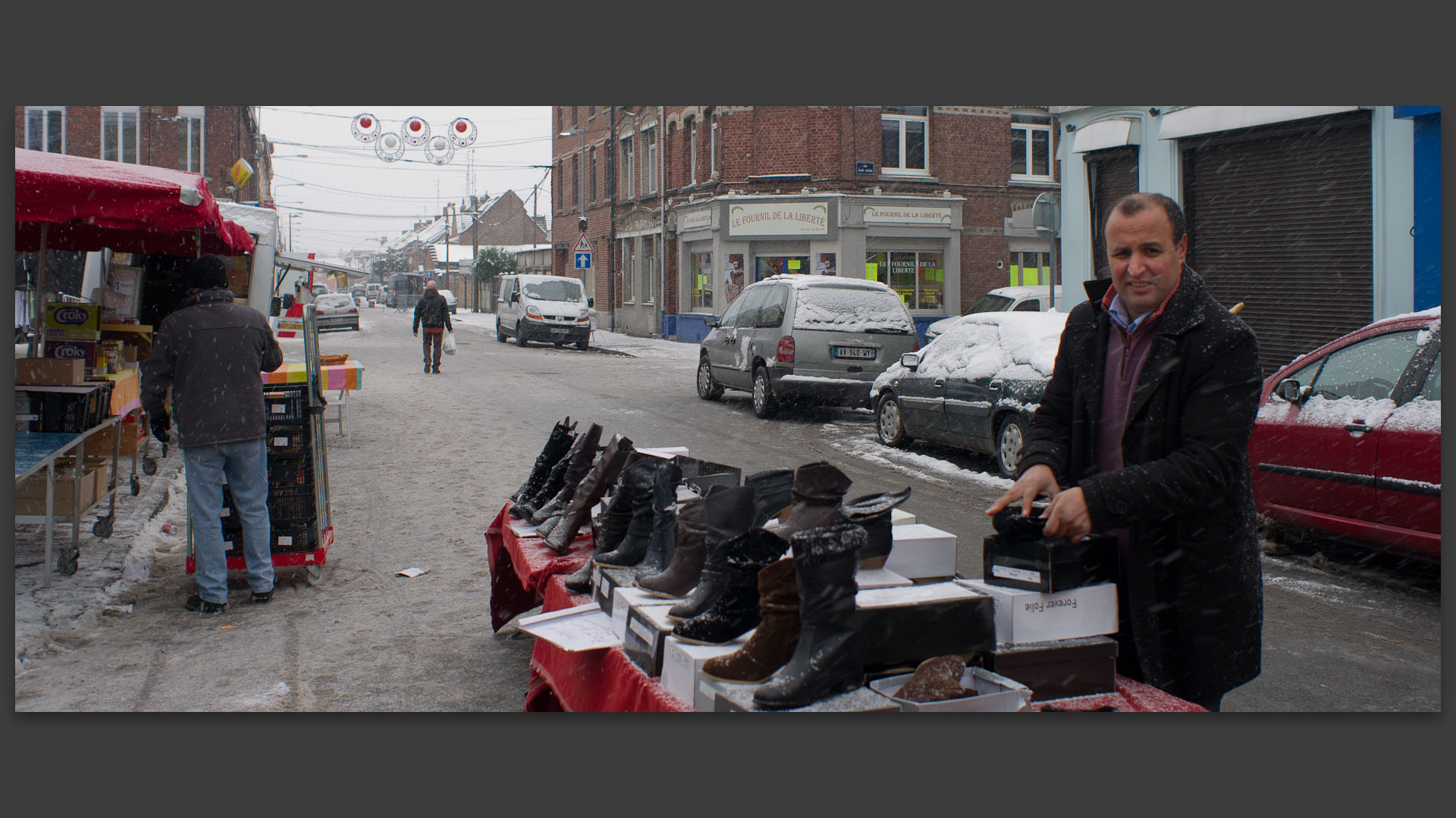 Marchand de chaussures sous la neige, au marché Saint-Pierre, place de la Liberté, à Croix.