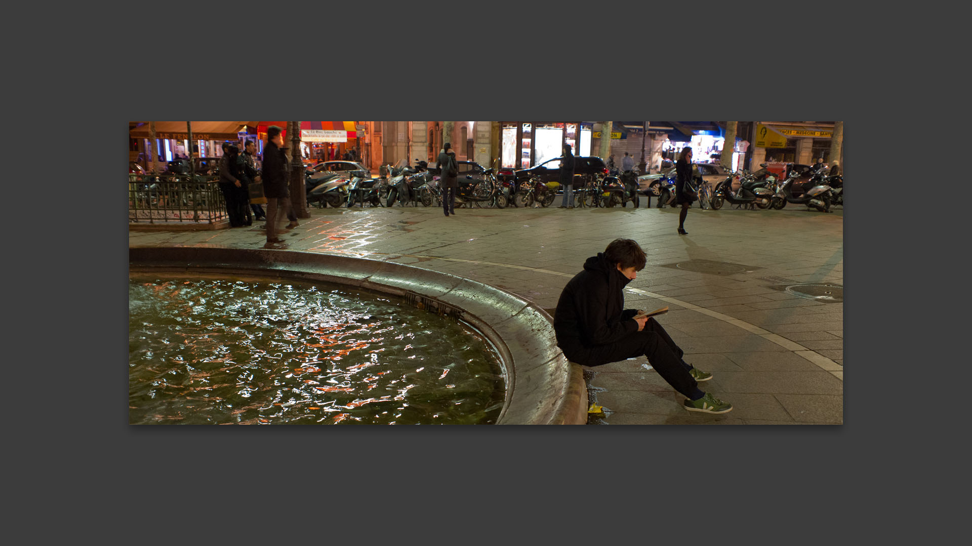 Jeune homme lisant, place Saint-Michel, à Paris.