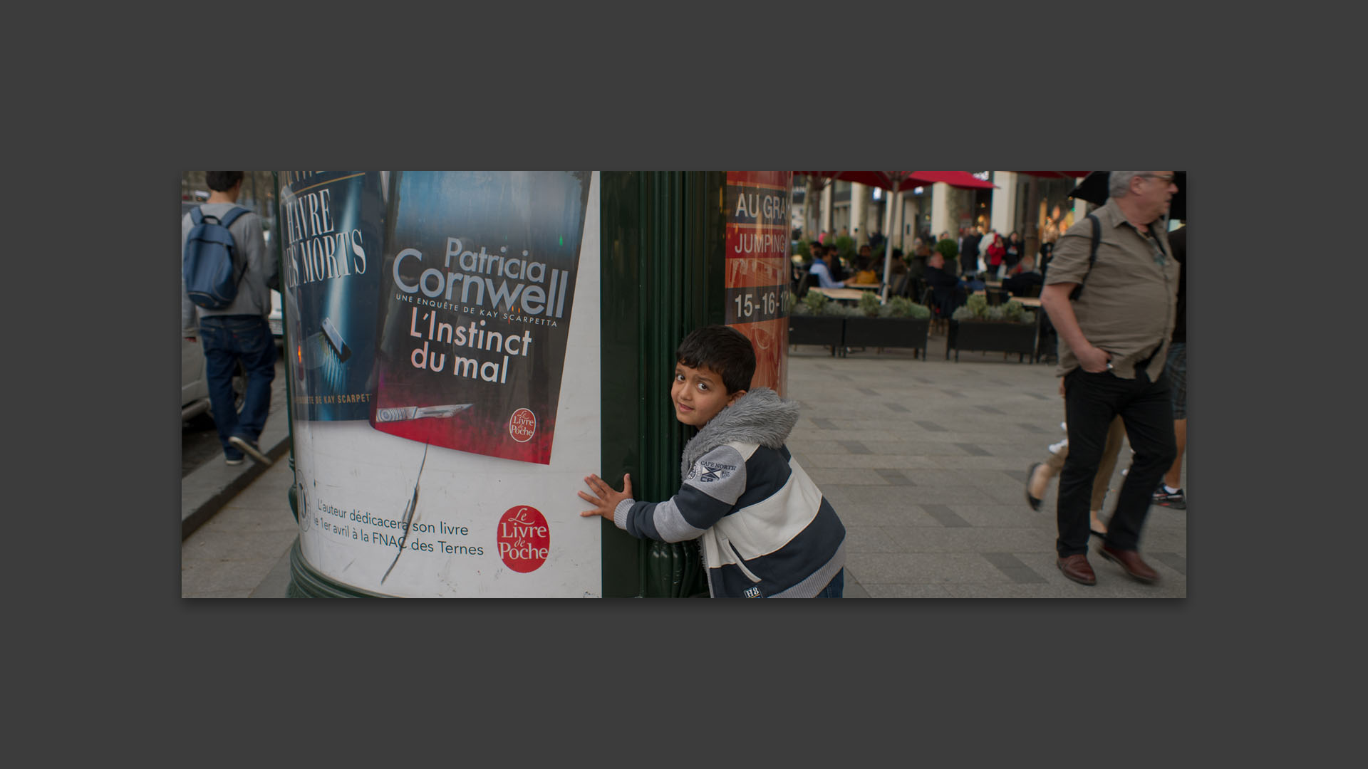 Gamin jouant à cache cache, avenue des Champs Elysées, à Paris.