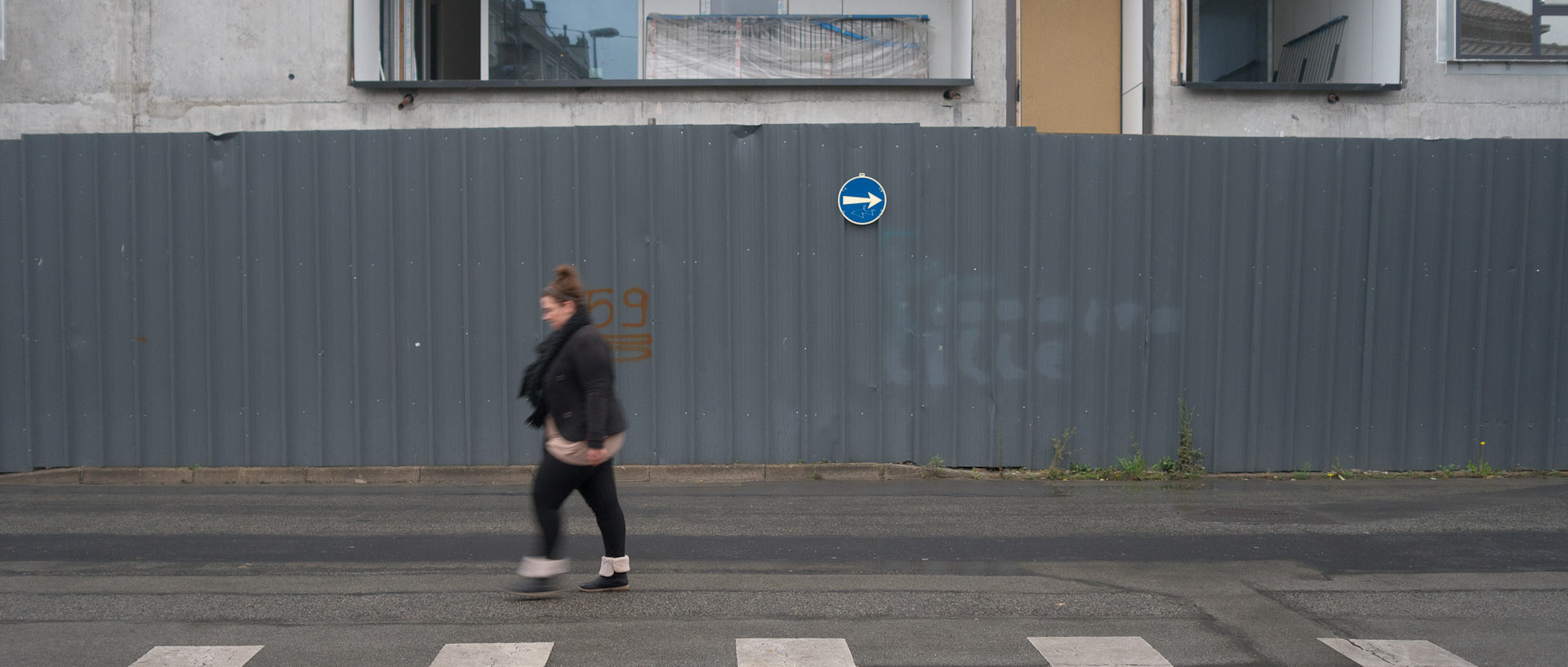 Jeune fille devant une palissade, rue de l'Amiral-Courbet, à Lille Fives.