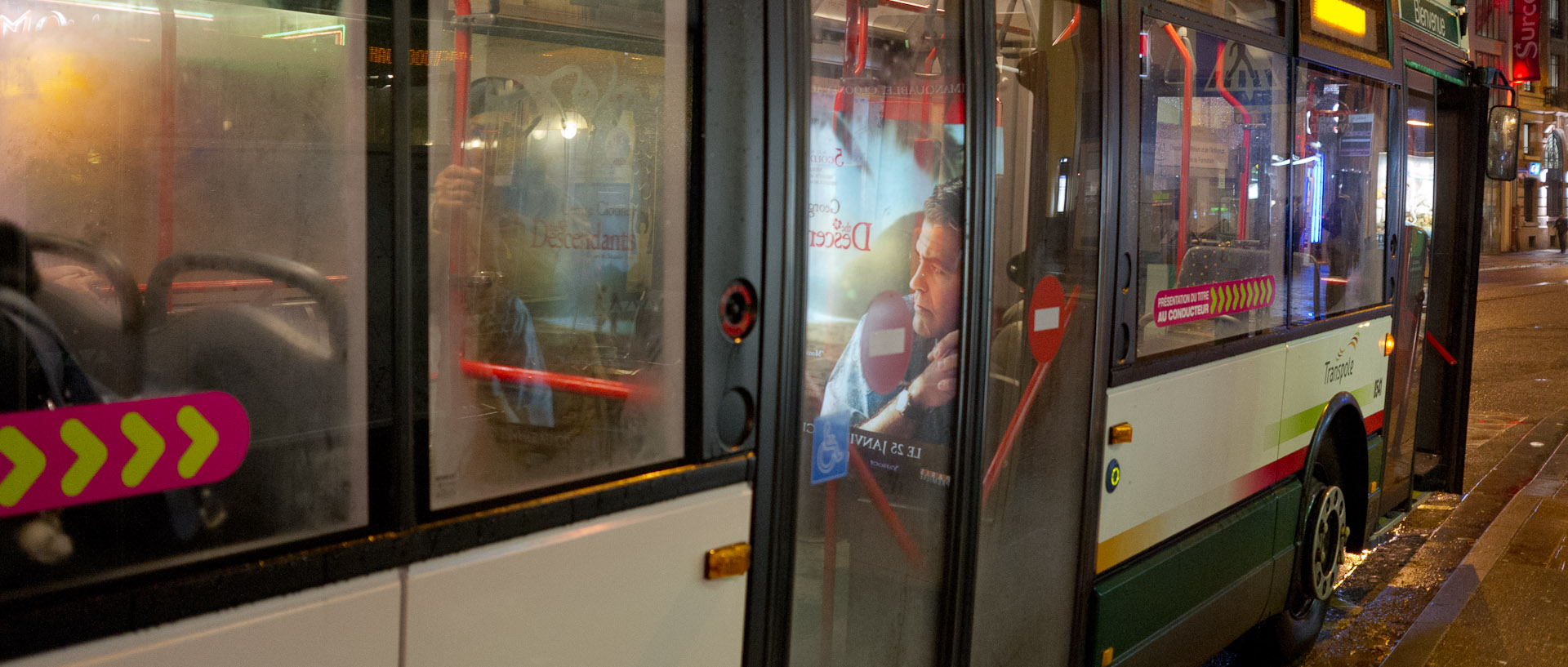 Reflet d'une affiche publicitaire pour un film dans la porte d'un autobus à l'arrêt, rue du Molinel, à Lille.