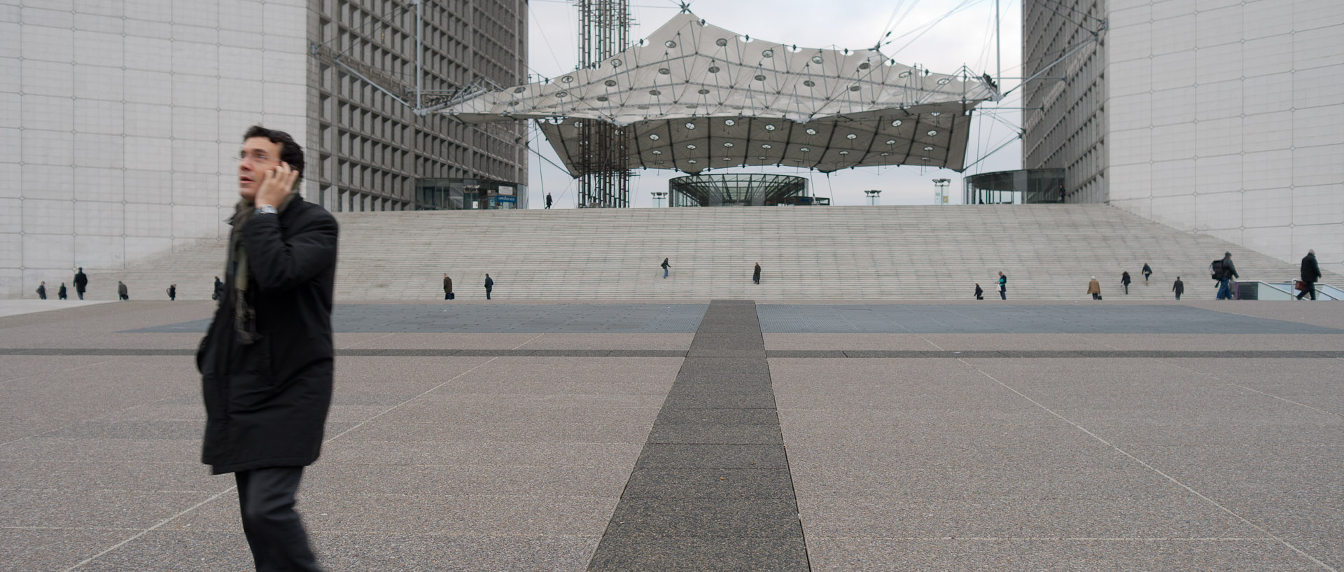 Homme avec un téléphone portable, esplanade de Paris La Défense.