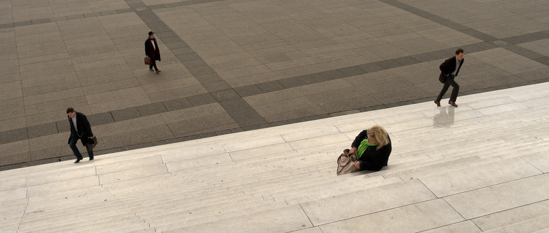 Femme assise sur les marches de la grande arche, à Paris La Défense.