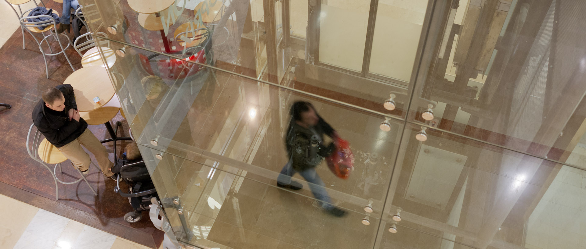 Reflet d'un homme dans une cage d'ascenseur vitrée, centre commercial des Tanneurs, à Lille.