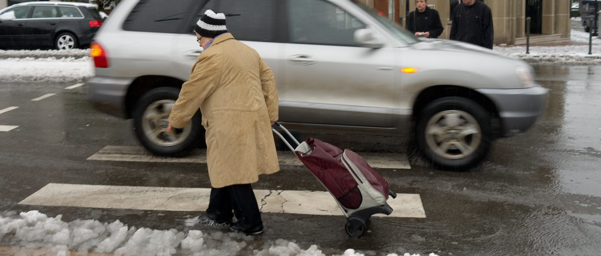 Vieille femme avec son caddie marchant dans une flaque de neige, rue Jean-Jaurès, à Croix.