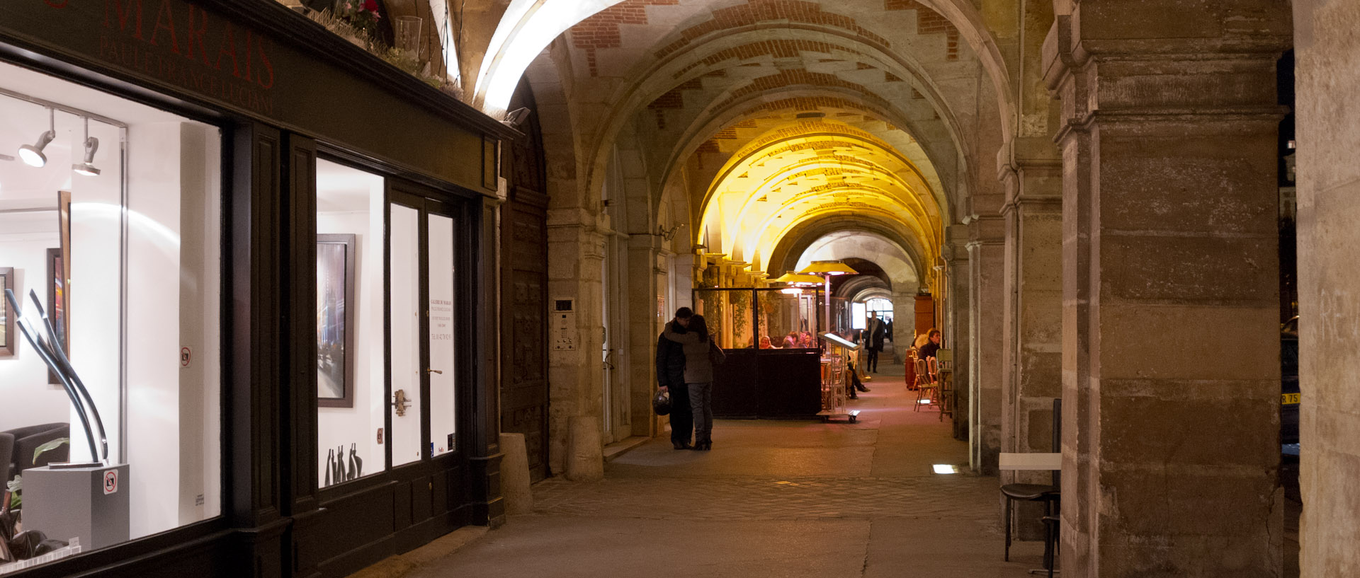 Amoureux sous les arcades de la place des Vosges, à Paris.