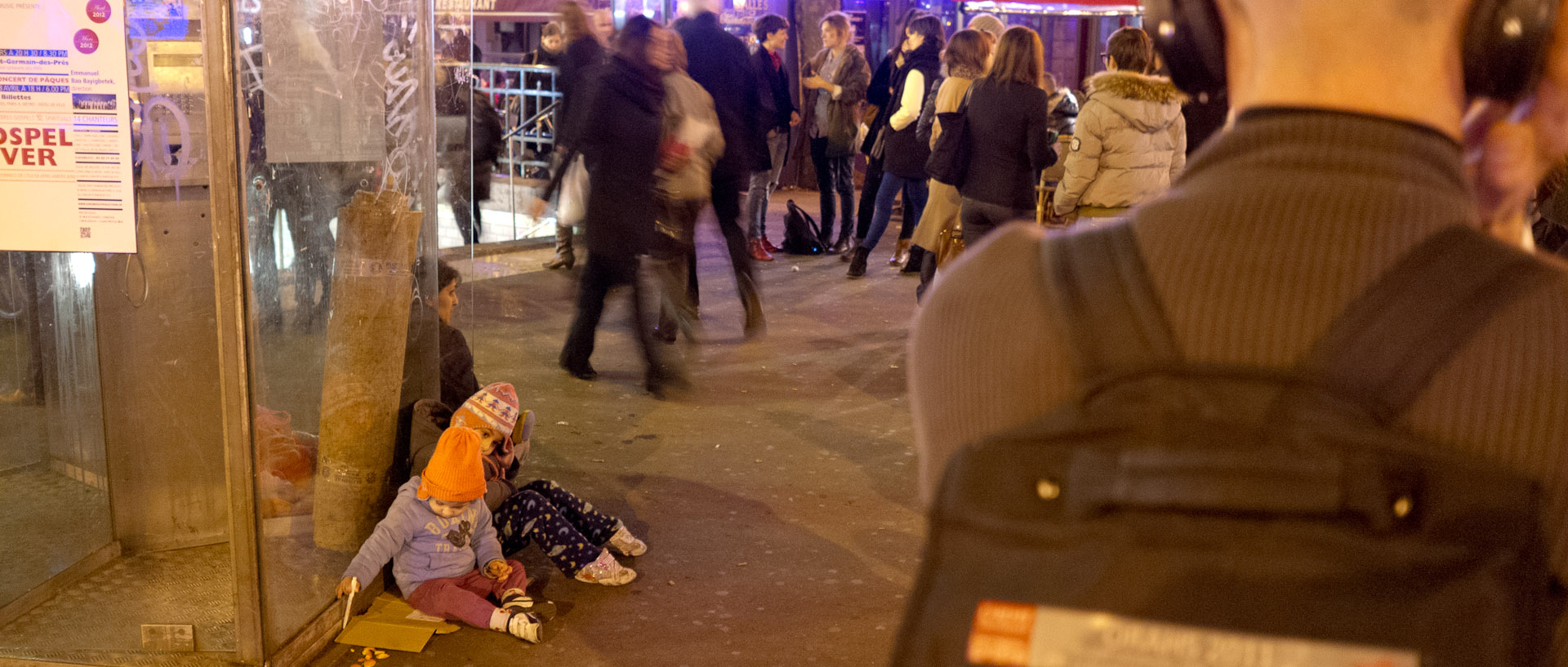 Enfants assis sur le trottoir, rue du Faubourg Saint-Antoine, à Paris.