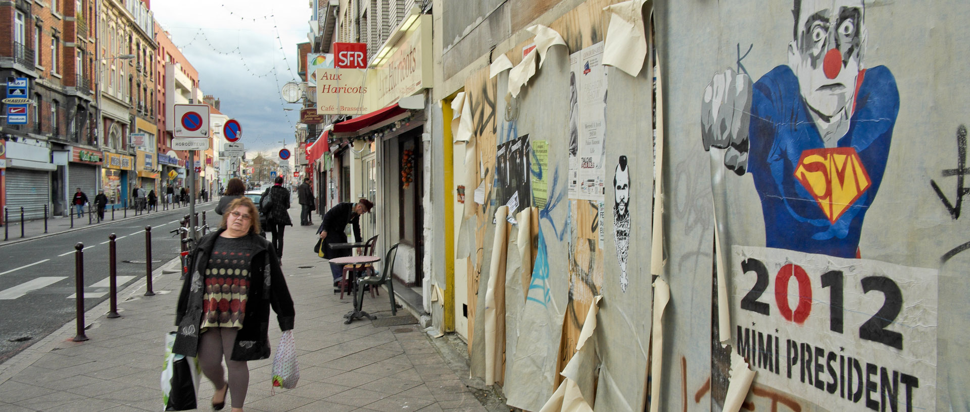 Passante devant une affiche humoristique, rue Gambetta, à Lille.