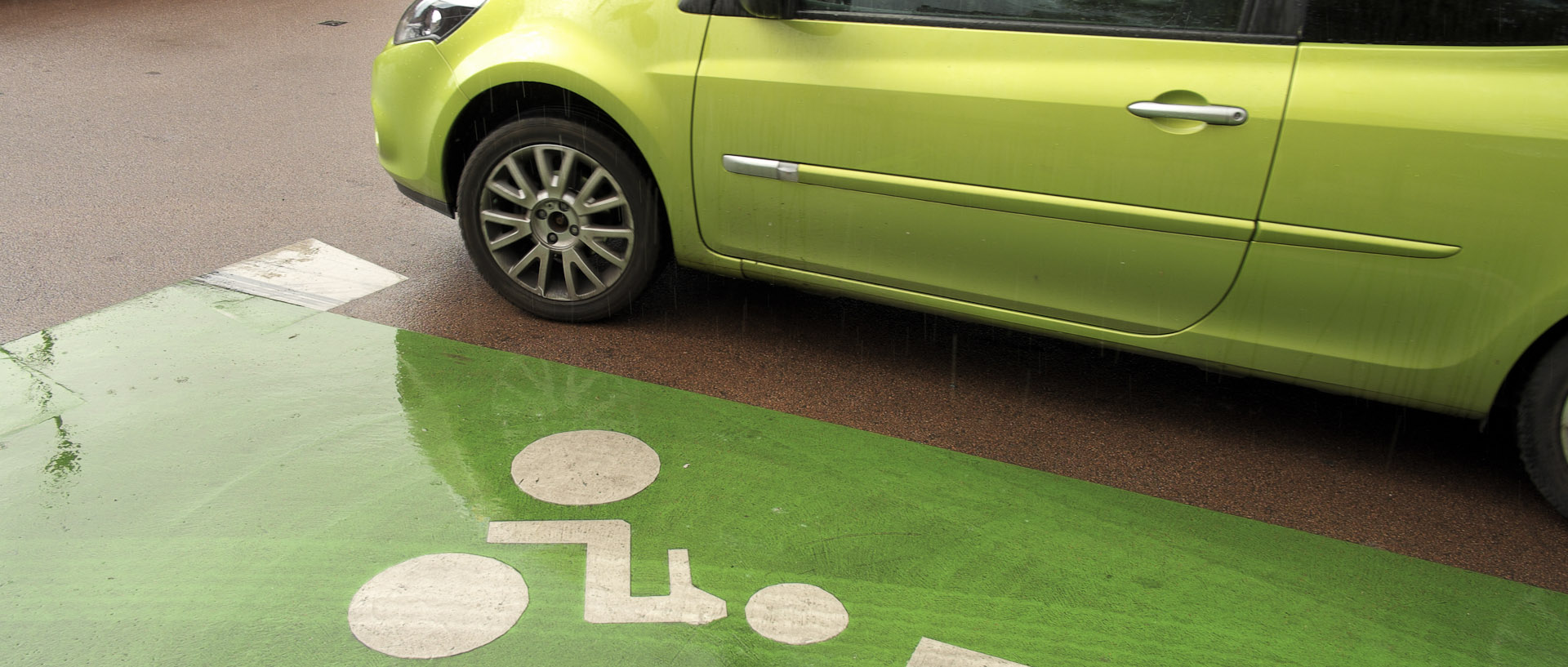 Voiture verte le long d'une piste cyclable verte, à Tourcoing.