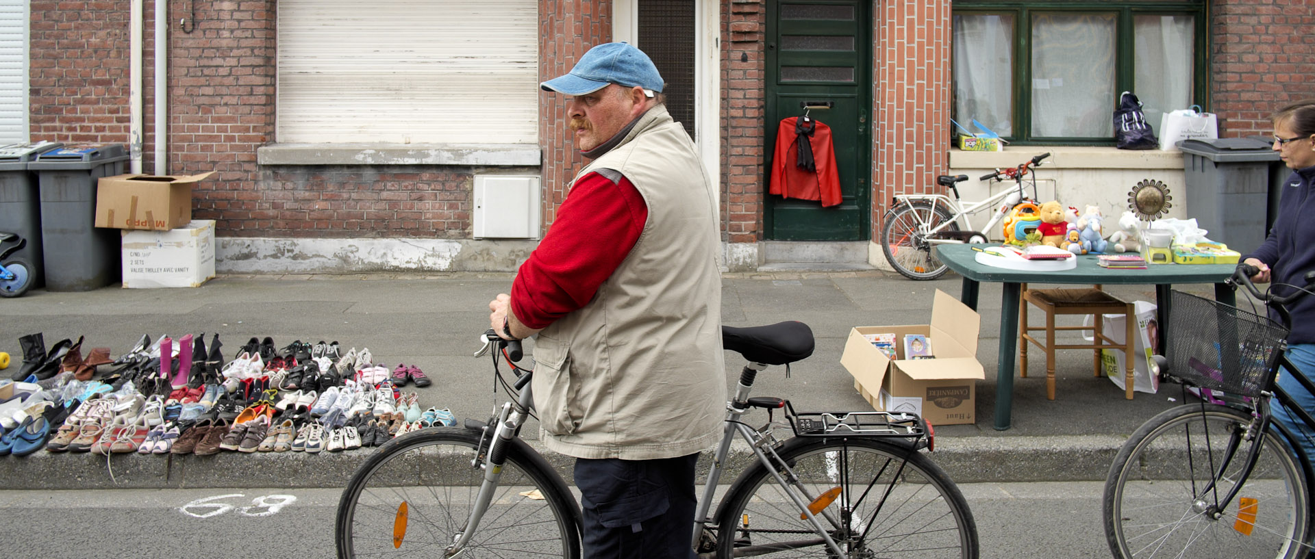 Cycliste passant devant des étals de braderie, rue Victor-Hugo, à Croix.