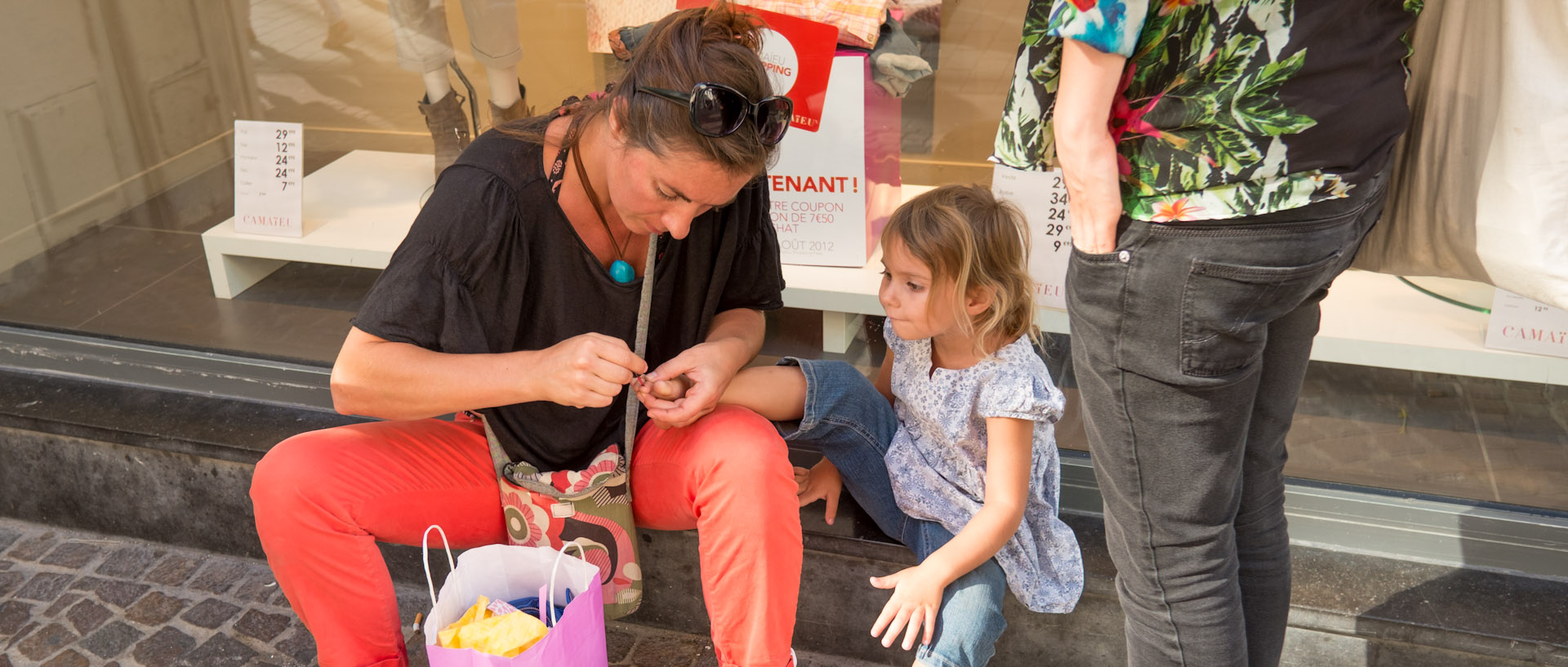 Mère appliquant du vernis à ongles sur les doigts de pied de sa petite fille, rue de Béthune, à Lille.