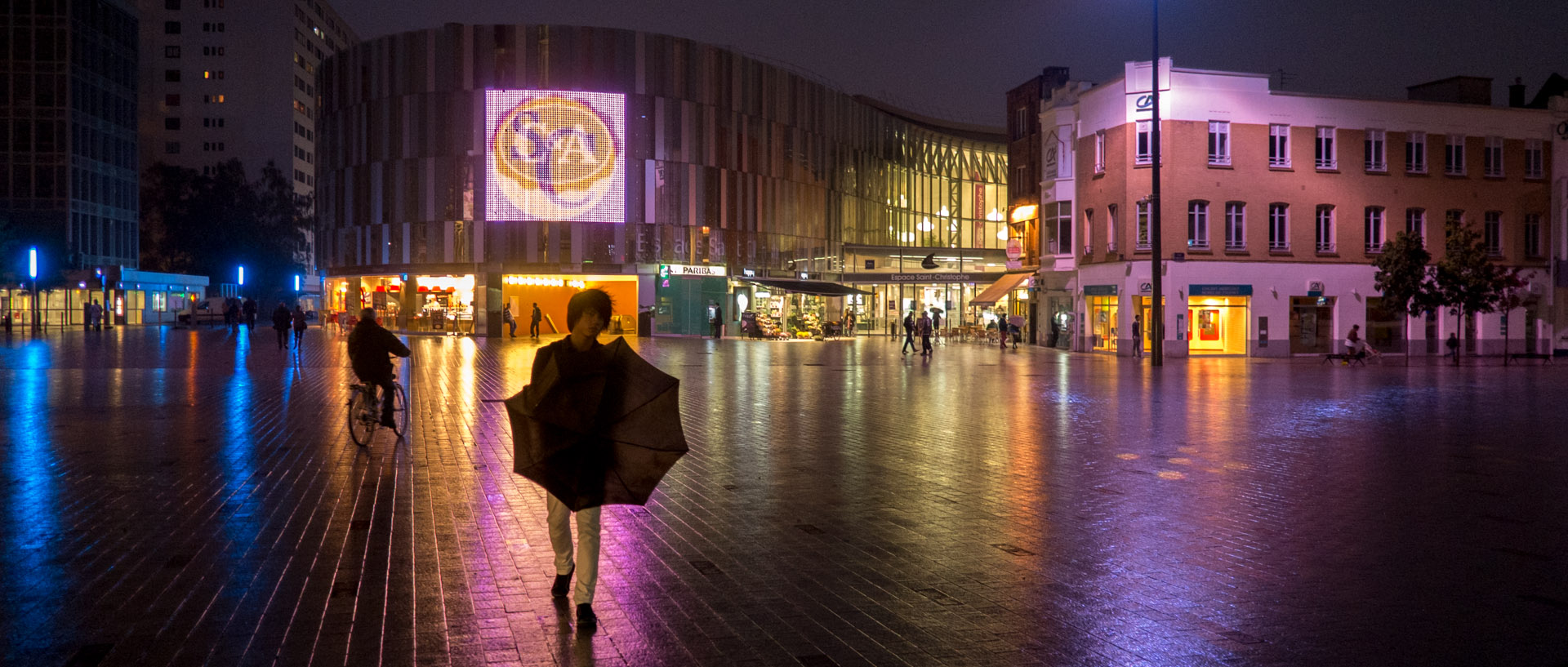 Homme avec un parapluie, devant l'espace Saint-Christophe, à Tourcoing.