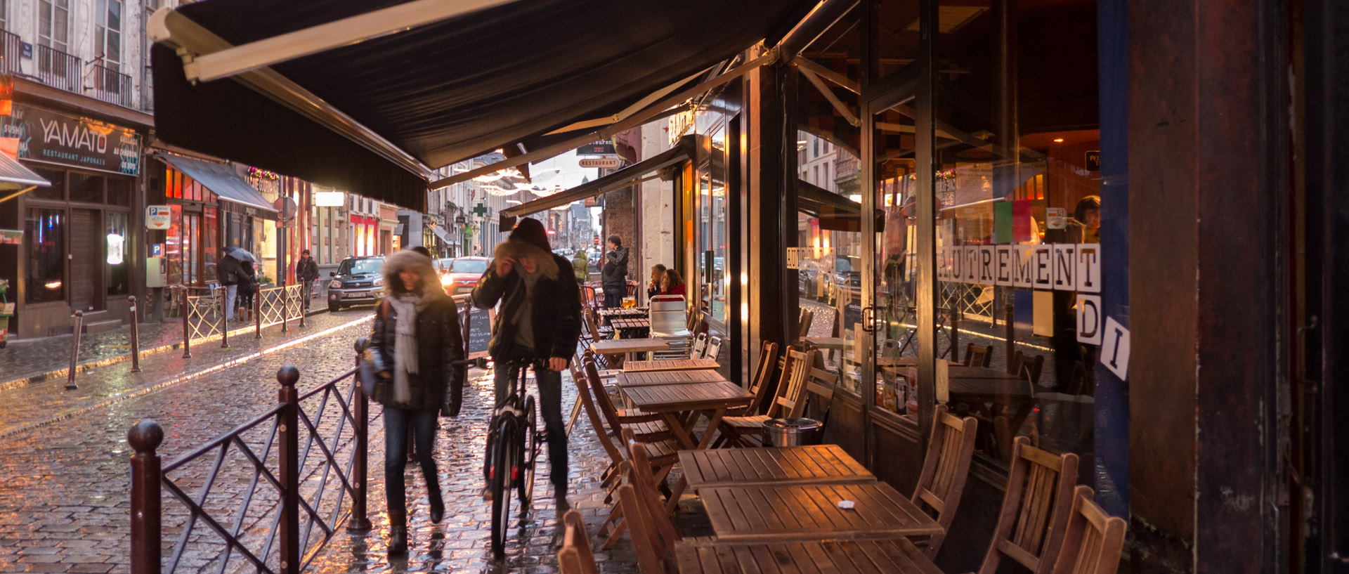 Couple sous la pluie, devant une terrasse de café, rue Royale, à Lille.