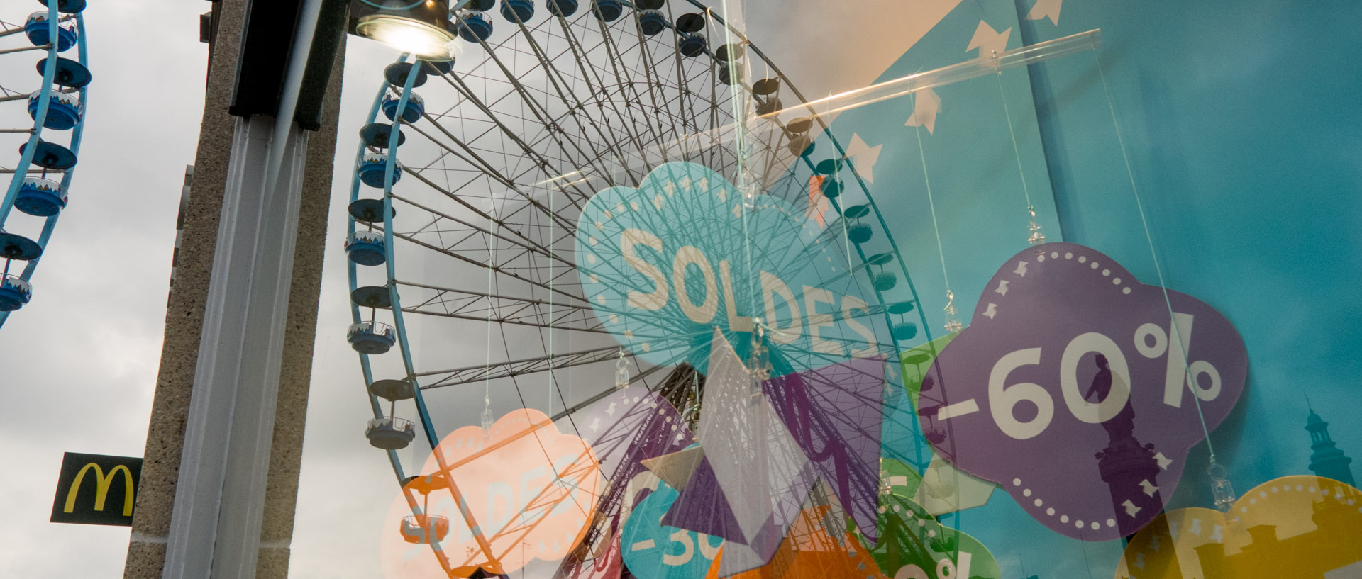 Reflet de la grande roue dans une vitrine affichant des soldes, place du Général-de-Gaulle, à Lille.