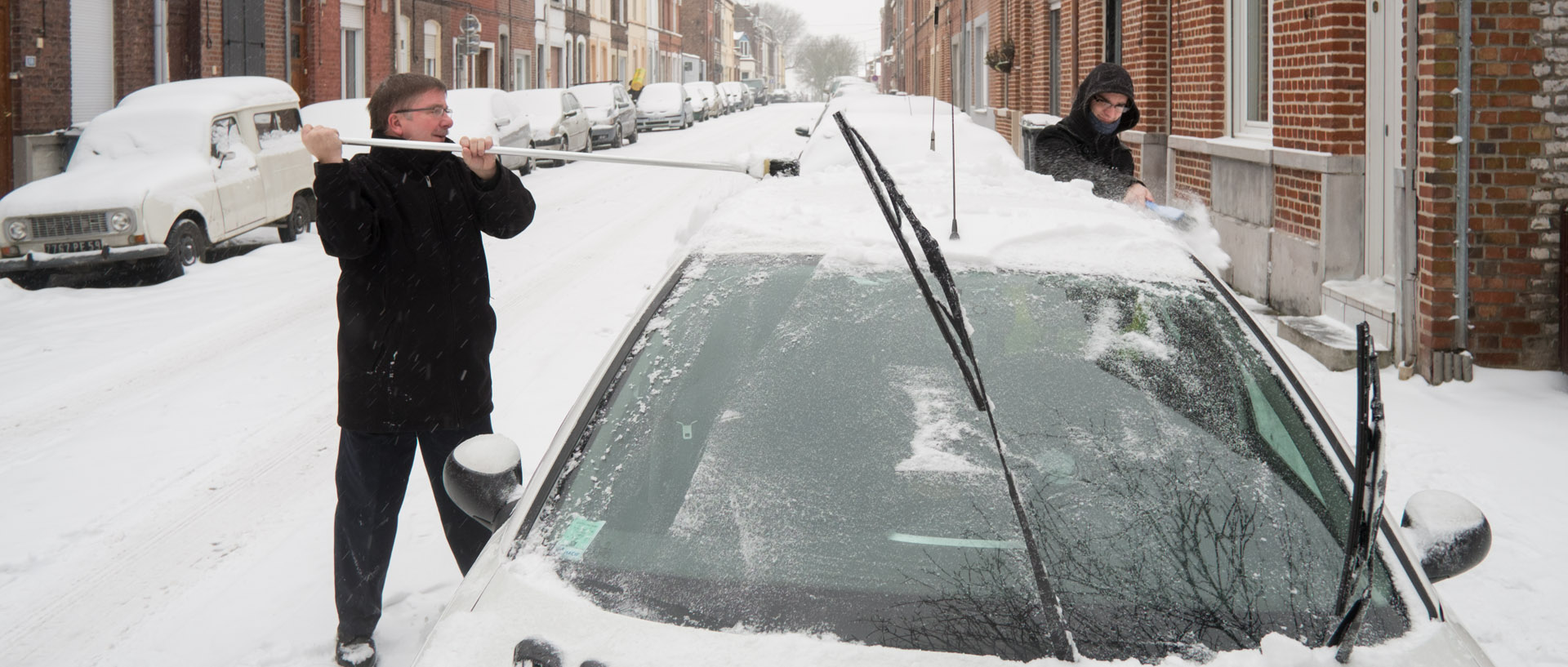 Déblayage de la neige sur une voiture, rue Francisco-Ferre, à Croix.