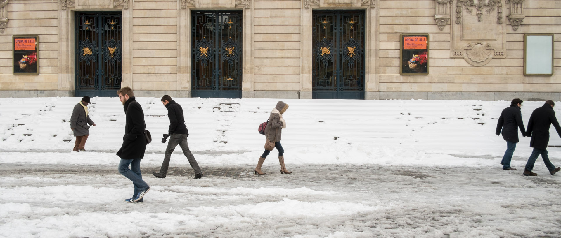 Passants devant l'opéra, sous la neige, place du Théâtre, à Lille.