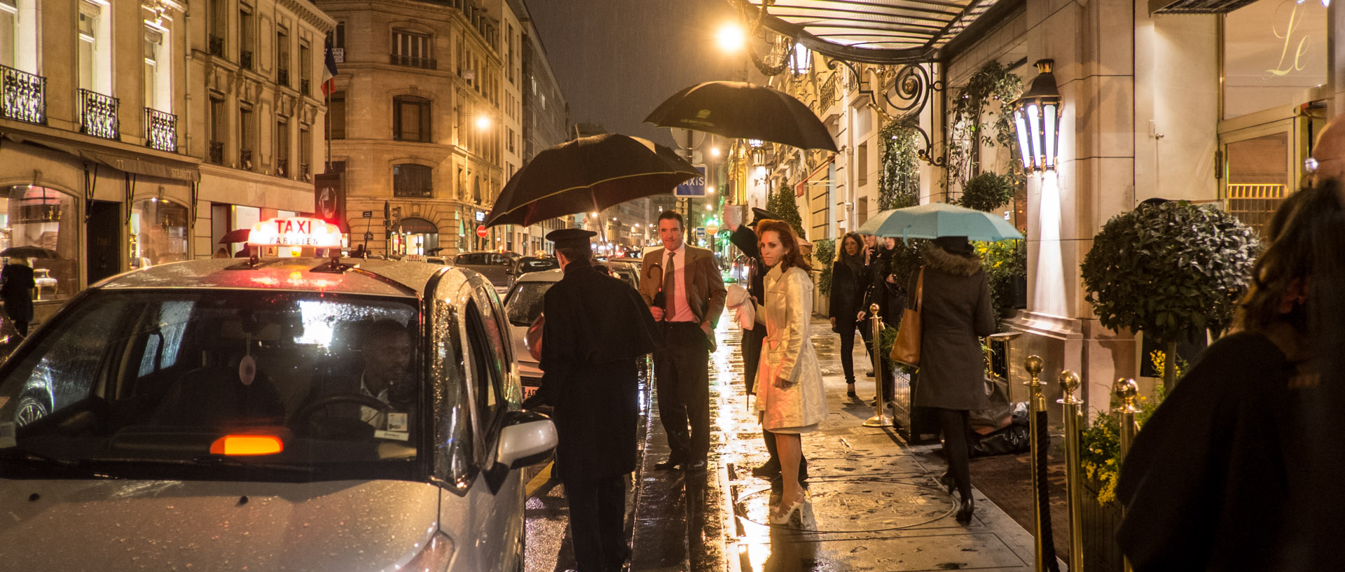 Clients d'un grand hôtel attendant leur taxi, rue du faubourg Saint-Honoré, à Paris.