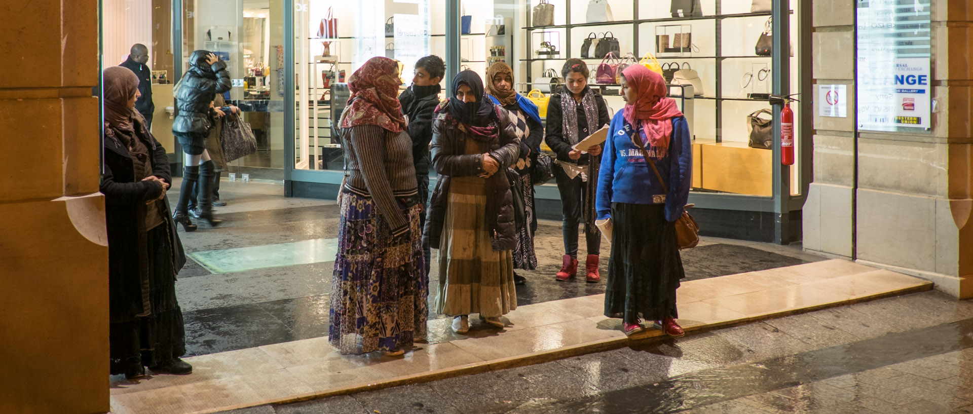 Roms s'abritant d'une averse dans une galerie marchande des Champs Elysées, à Paris.