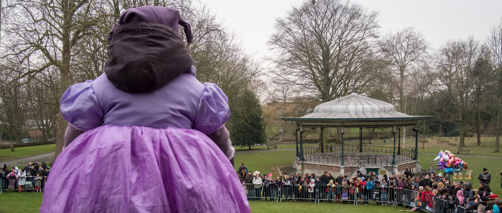 Fillette sur les épaules de son père, attendant le défilé de carnaval, dans le parc de la mairie de Croix.